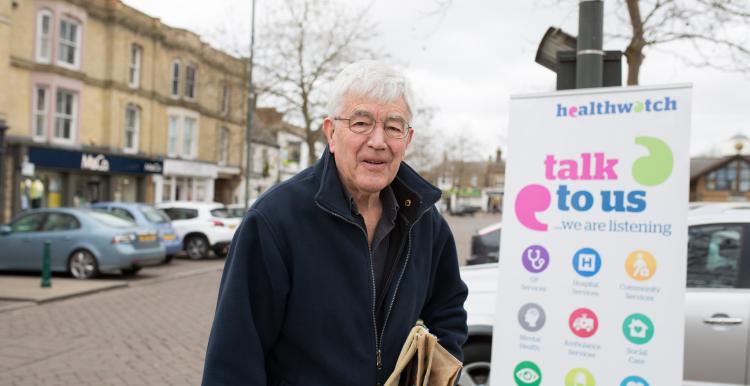 Elderly gentleman standing in front of a Healthwatch banner